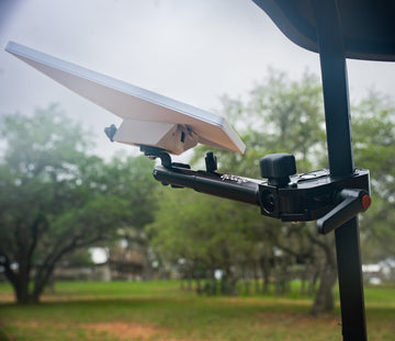 Starlink Mini mounted on an Altangle Connect arm clamped to a vertical roll-cage post, dish angled skyward with oak trees behind