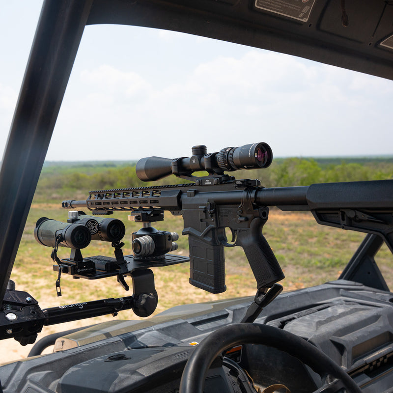 Hub clamped to a truck bed rail with a hunting rifle in an Arca plate, predawn light