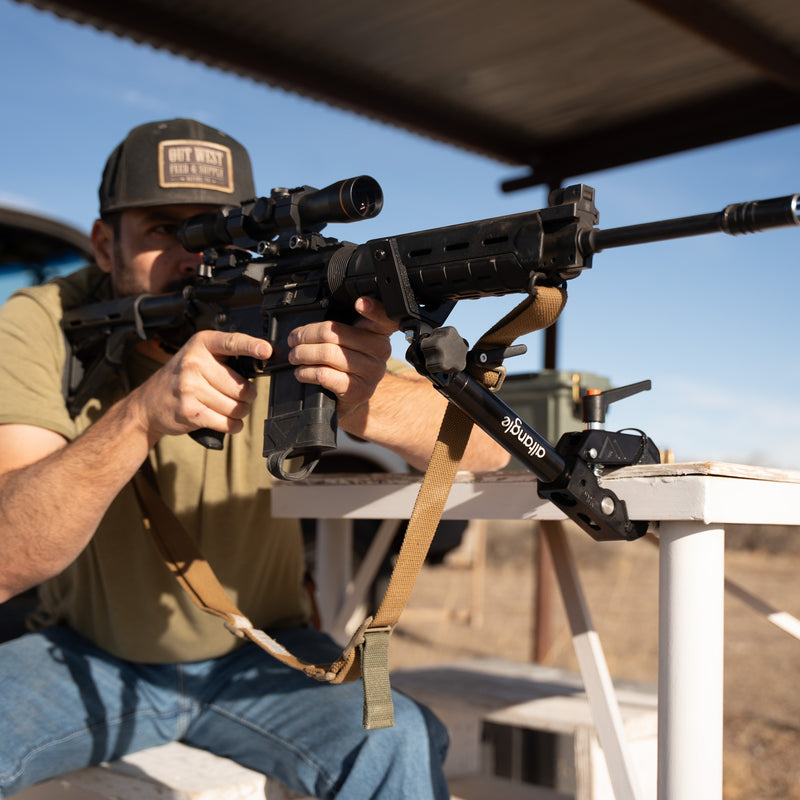 Hub clamped to a truck bed rail with a hunting rifle in an Arca plate, predawn light